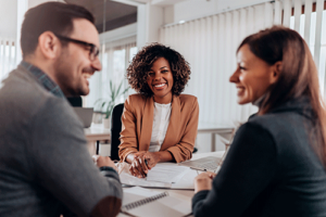 a woman smiles while speaking to two people about consulting services for mental health treatment centers