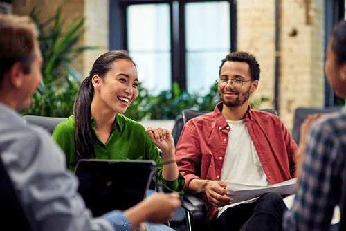 woman in green shirt sits with a group of people and laughs while others look at her